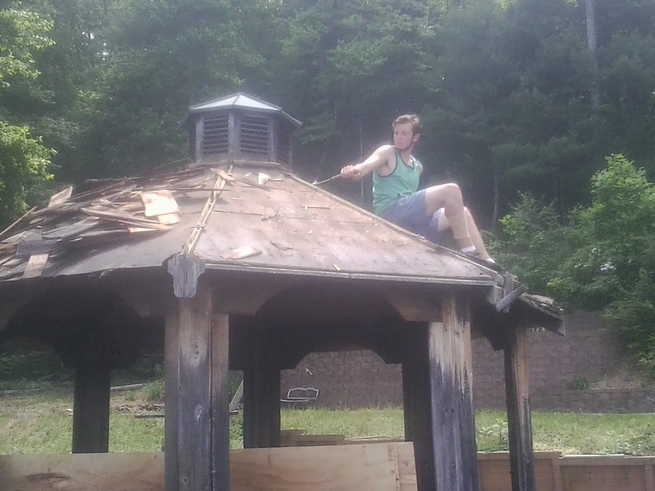 Tearing the old roof off a wooden gazebo before new shakes in Dittmer