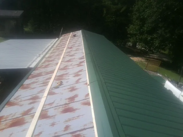 Old rusted panels beside newly installed green metal roofing — Wind Damage Roof Repair by Roofing Brothers in Dittmer