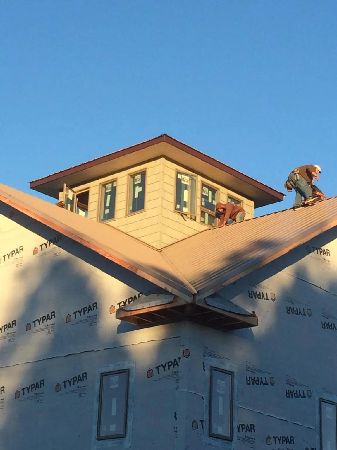 Roofers working around a rooftop cupola on a new metal roof at sunset — Roof Waterproofing in Dittmer by Roofing Brothers